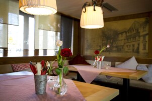 Un comedor con mesas, sillas y un florero con una rosa.