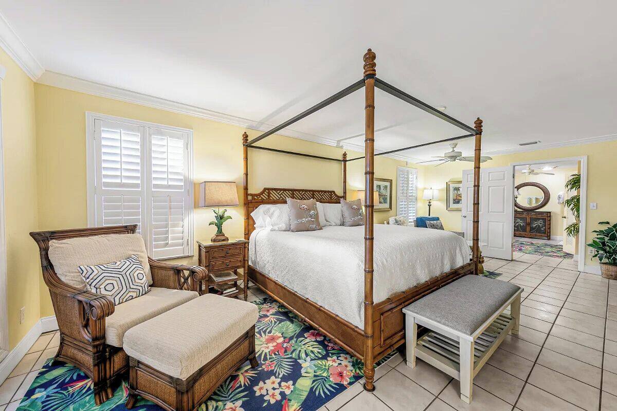 A four-poster bed with a wooden frame and a bench at the foot of the bed.