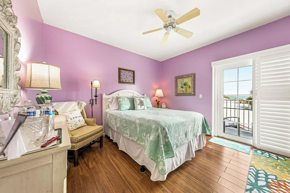 A bedroom with a bed, a nightstand, a chair, a ceiling fan, and a window with blinds.