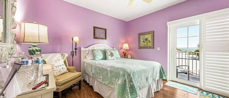 A bedroom with a bed, a nightstand, a chair, a ceiling fan, and a window with blinds.