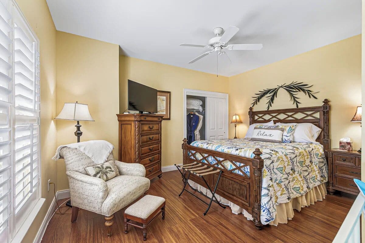 A bedroom with a wooden bed, a chair, a desk, and a wardrobe.