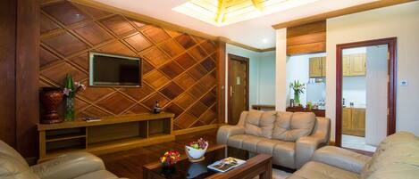 A living room with a wooden ceiling, a flat-screen TV, a coffee table with a bowl of fruit, and two sofas.