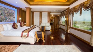 A spacious hotel room with a large bed, a leather armchair, and a view of the outdoors. - Hotel Shwe Pyi Thar (Mandalay)