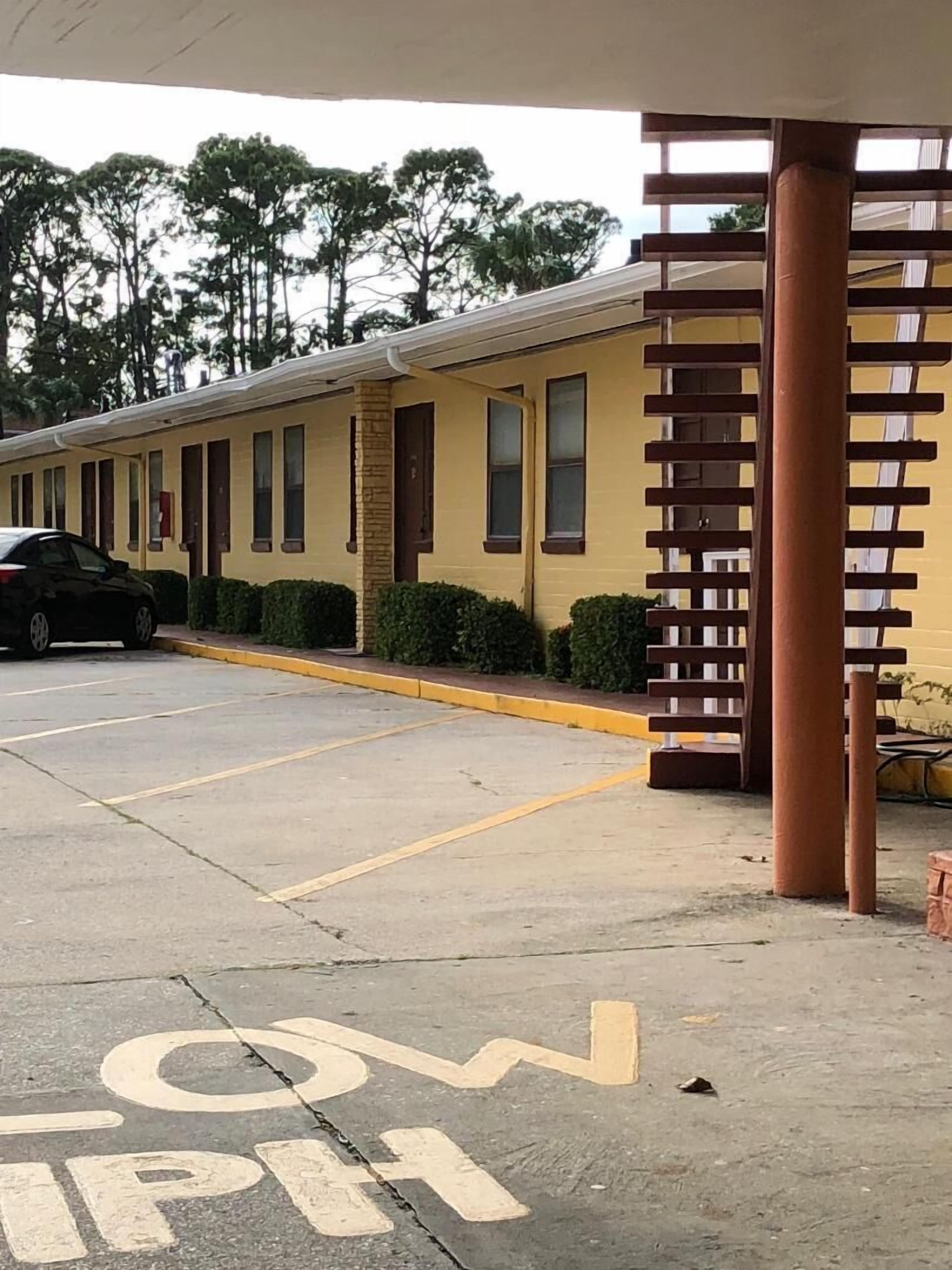 A yellow building with a parking lot in front.