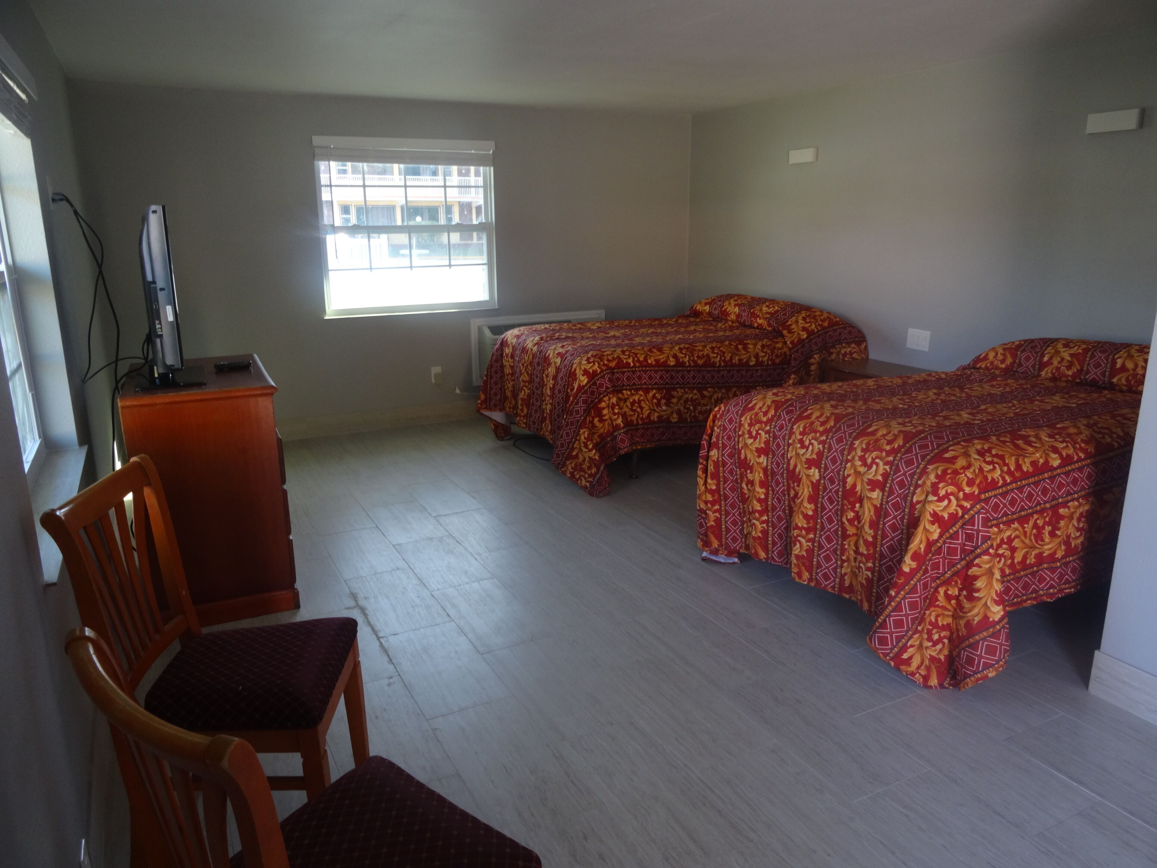 A room with two beds, a desk, and a chair.