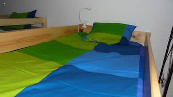 Una cama de madera individual con colcha azul y verde.