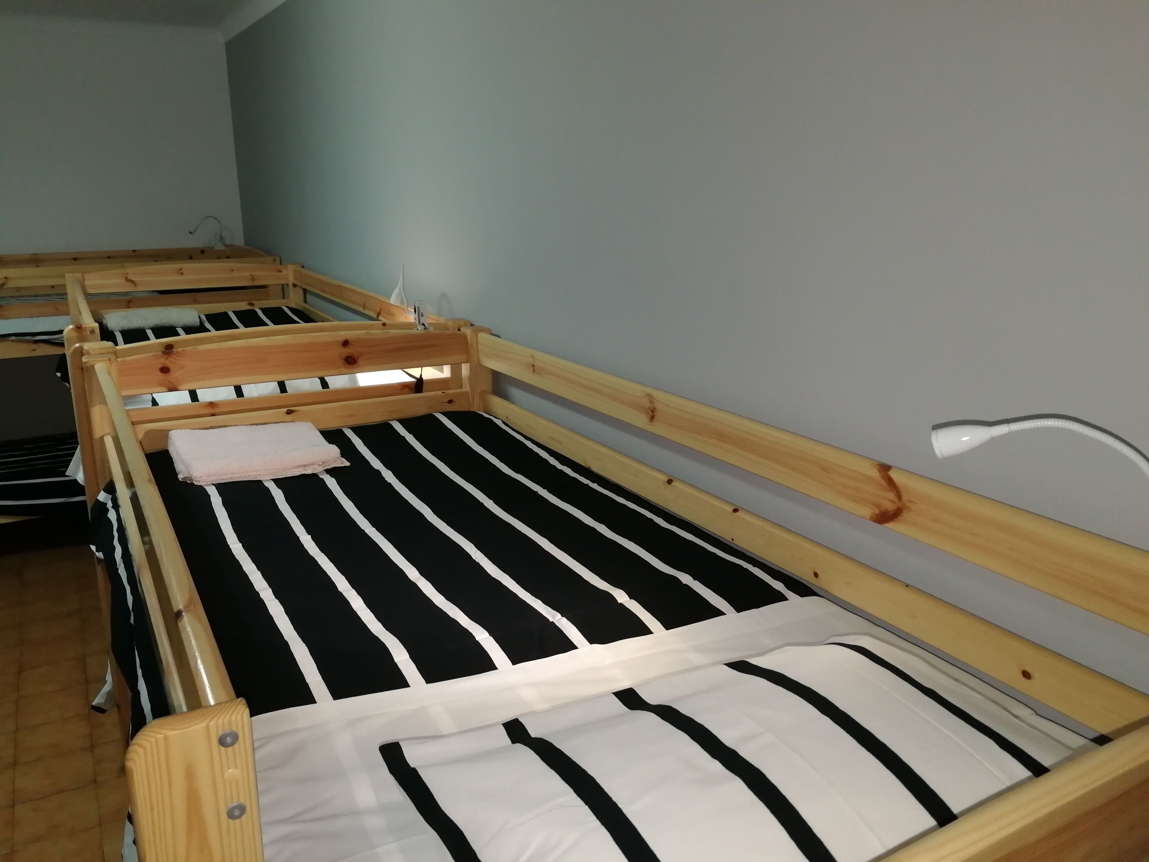 A bunk bed with a black and white striped mattress and a wooden frame.