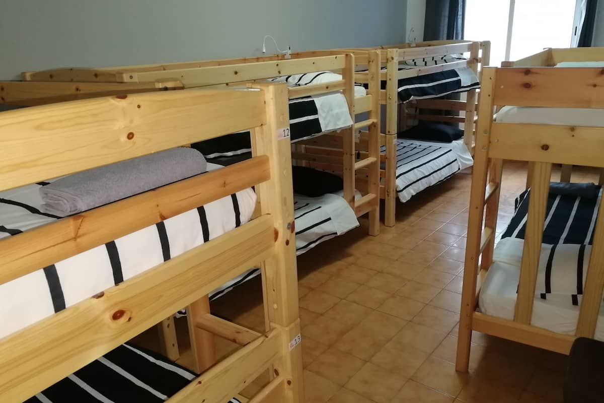 A row of bunk beds in a room with tiled flooring and a window providing natural light.