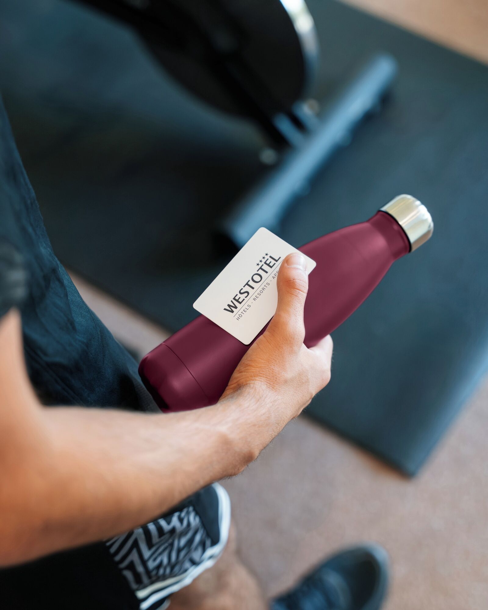 A person holding a bottle with a label that reads "WESTOTEL" and mentions "HOTELS, RESORTS, APPS."
