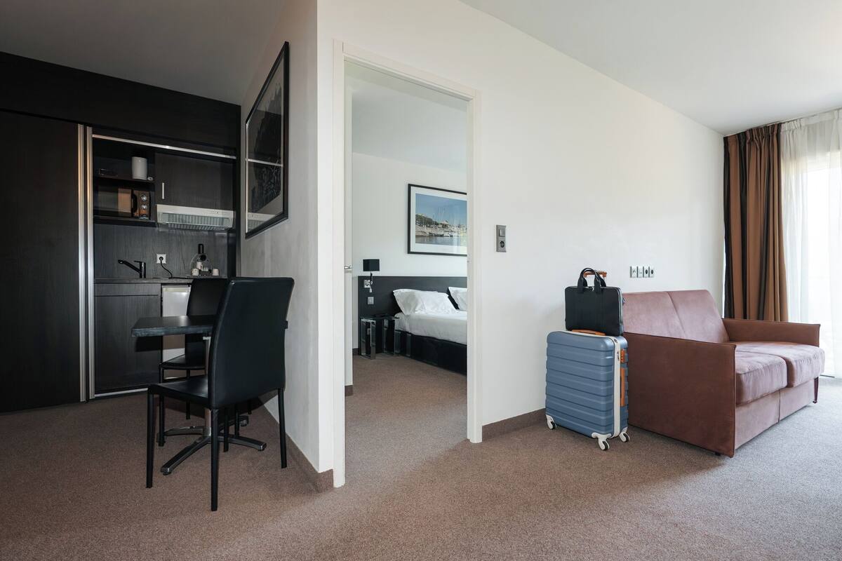 Habitación de hotel con kitchenette, una cama, escritorio y zona de estar.
