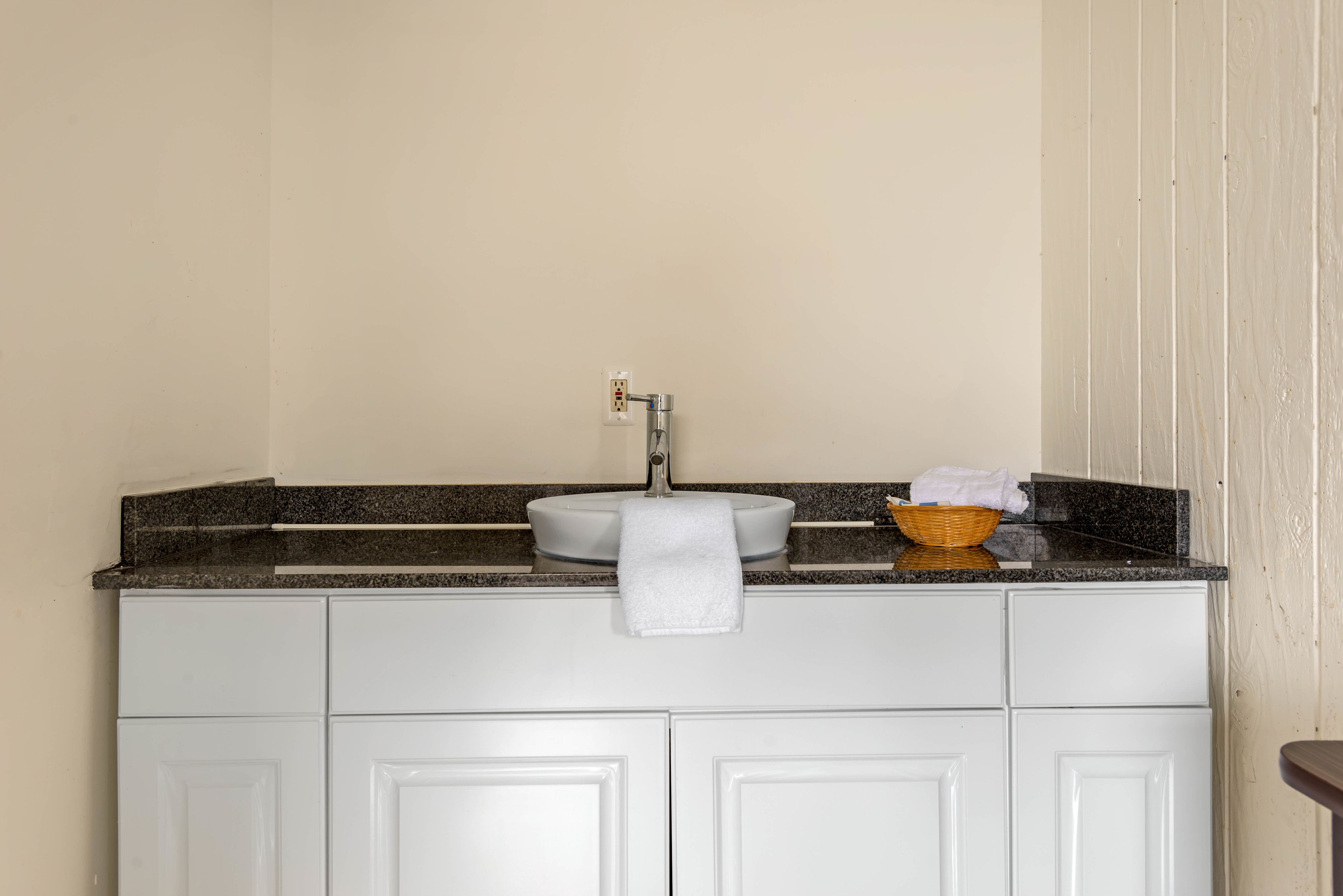 A bathroom with a white vanity, a sink, and a towel hanging on the wall.