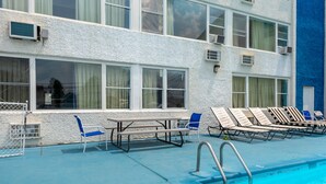 Un espace piscine aménagé avec des chaises longues, une table et un escalier pour accéder à la piscine.
