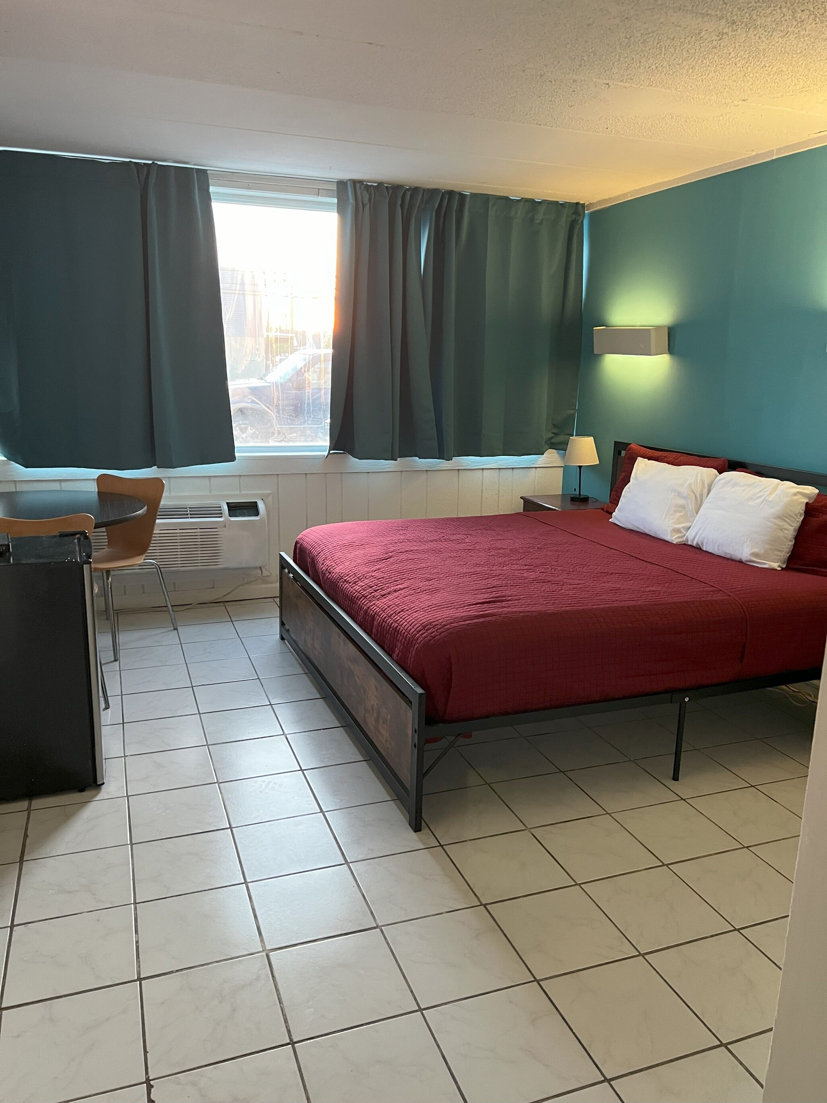 A bedroom with a bed, a desk, and a chair.
