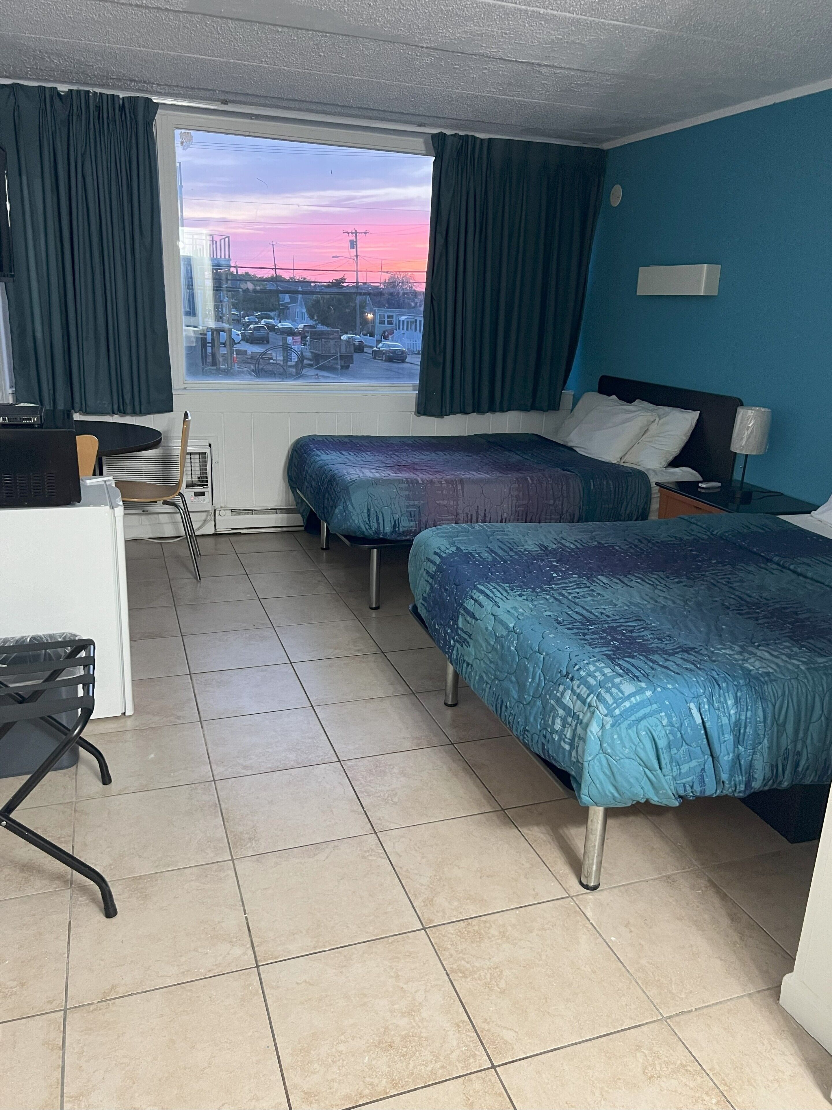 Habitación de hotel con dos camas, un escritorio, una silla y vistas a la ciudad.
