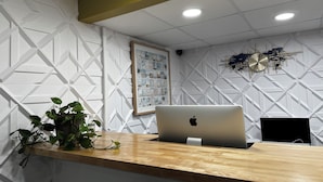 Un comptoir d’accueil avec un ordinateur portable, un montage de photos encadrées et une plante en pot.