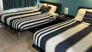 Une chambre d’hôtel avec deux lits, des murs de couleur turquoise et une fenêtre avec des rideaux.