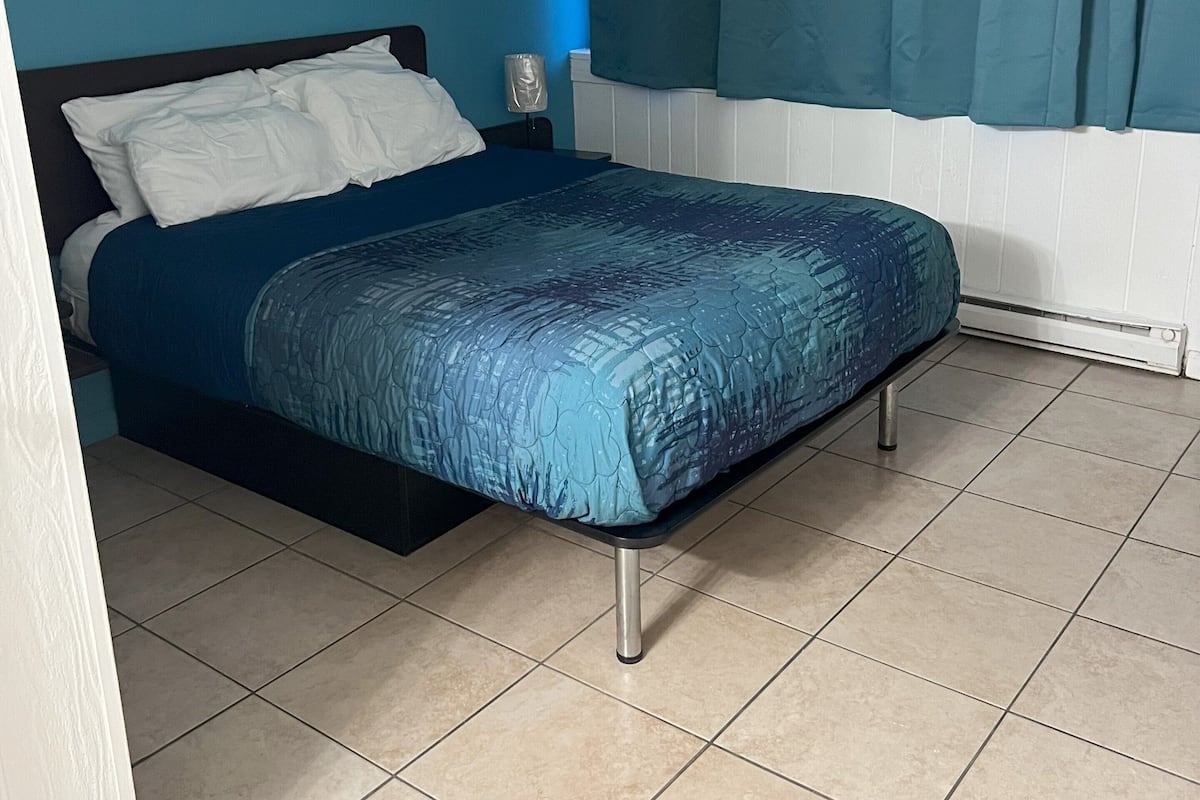 Ein Schlafzimmer mit einem Bett, einem Nachttisch und einem Fenster mit Vorhängen.