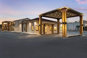 A hotel entrance with a covered waiting area, a parking lot, and a Starbucks Coffee shop in the background. - Red Roof Inn Houston – Spring North (Spring)