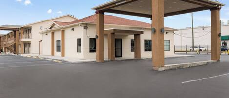 A multi-story hotel with a covered entrance and a parking lot.