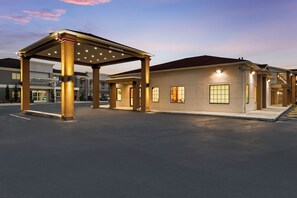 A hotel entrance with a covered waiting area and a building with multiple windows. - Red Roof Inn Houston – Spring North (Spring)