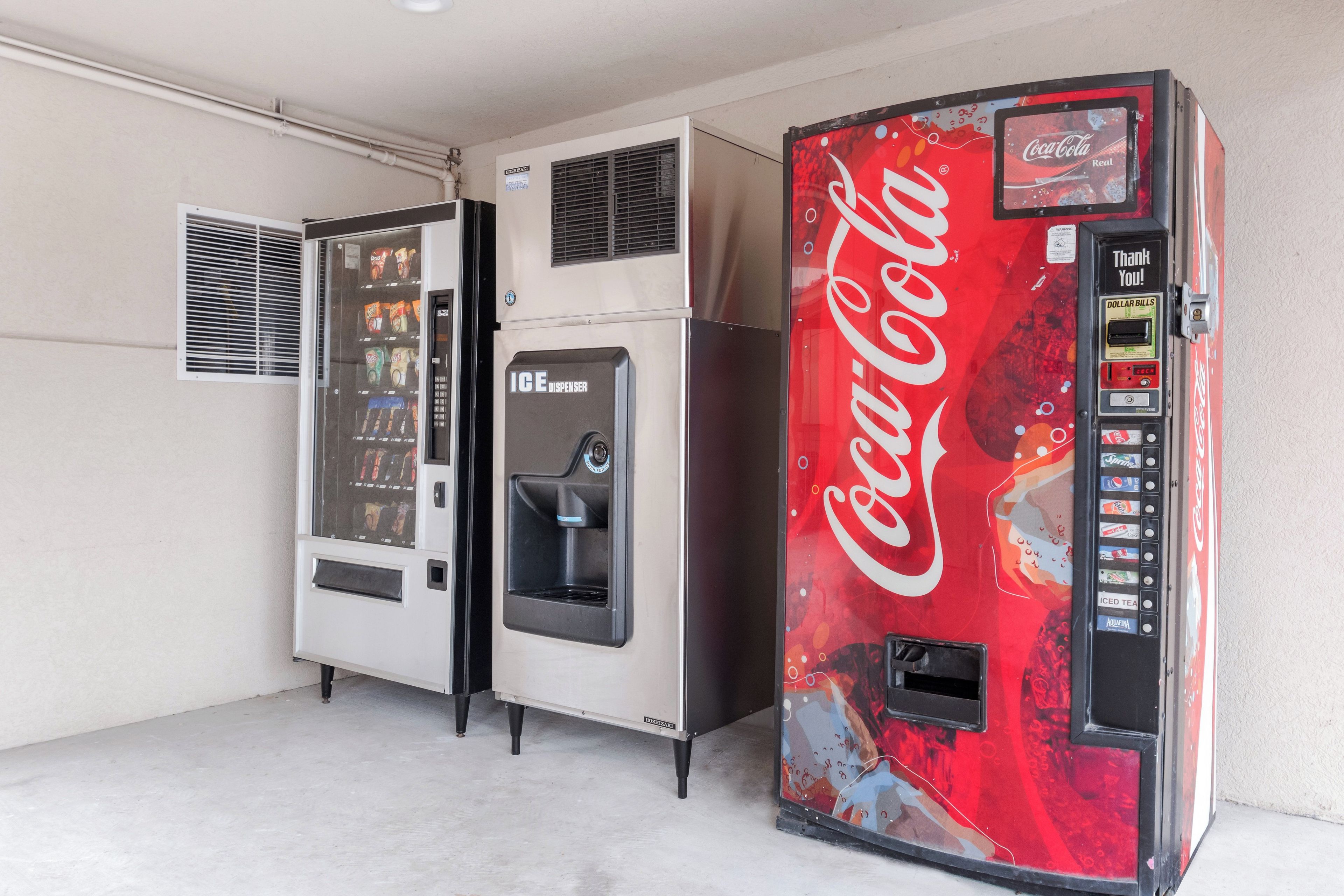 Máquinas expendedoras, una con dispensador de Coca-Cola y otra de snacks.