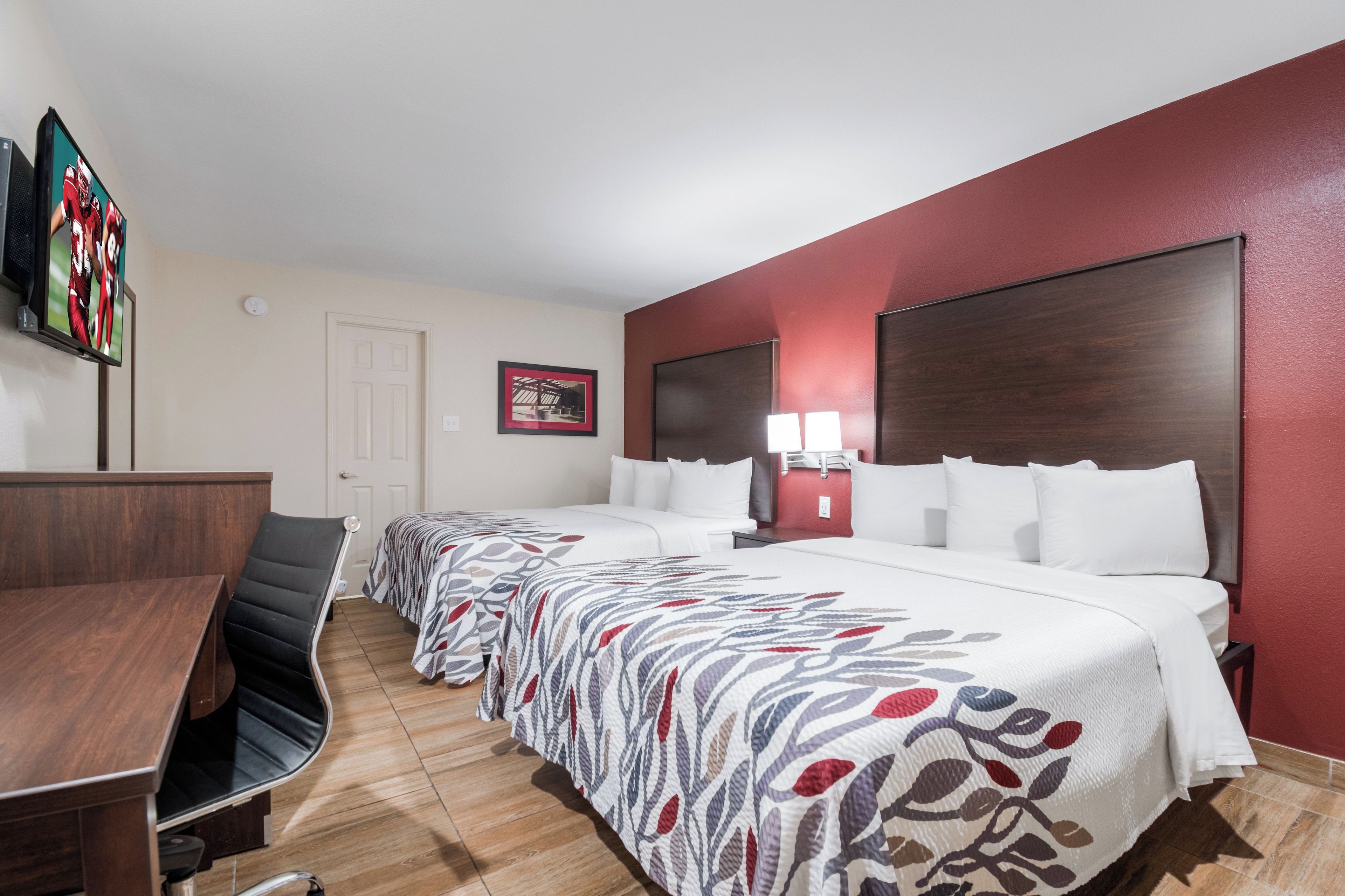 A hotel room with a large bed, two bedside tables, a desk, and a chair.