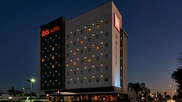 Experience the ibis Hotel's sleek, symmetrical facade with evenly spaced windows and a flat roof.
