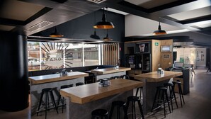 A modern restaurant interior with high tables and bar stools, a large window with a view, and pendant lighting. - Ibis Los Mochis (Los Mochis)