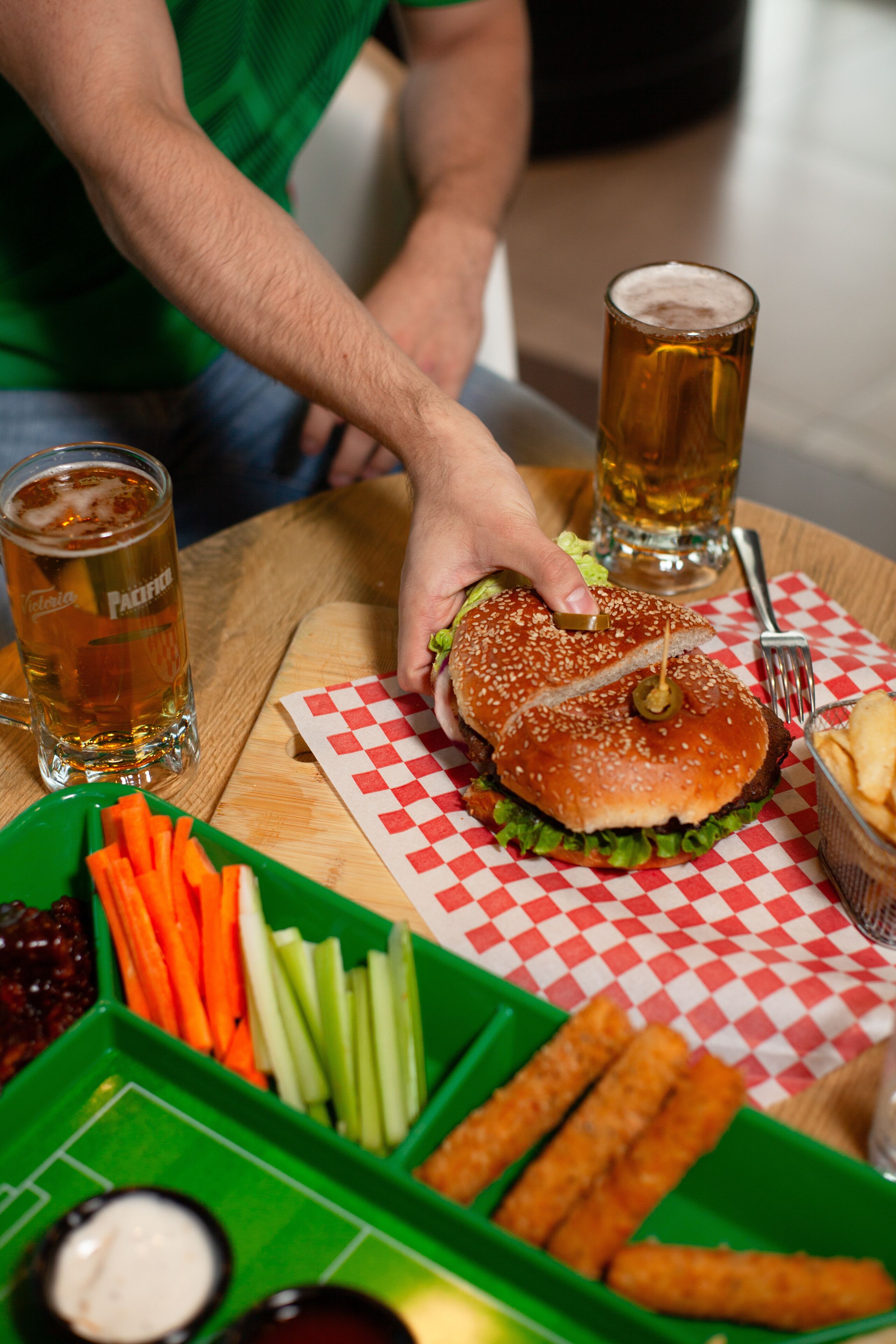 A meal with a burger, vegetables, and dipping sauces on a table.