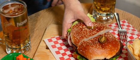 A meal with a burger, vegetables, and dipping sauces on a table.