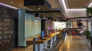 A modern bar area with a long counter, bar stools, and pendant lighting. - Ibis Los Mochis (Los Mochis)