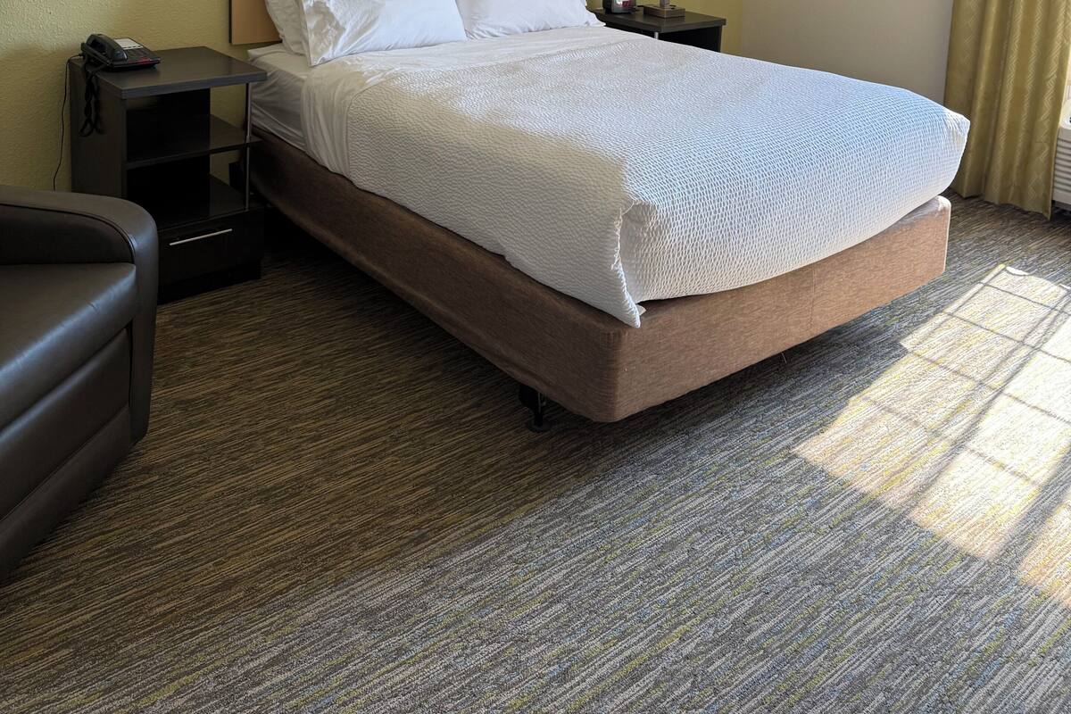 A hotel room with a large bed, two bedside tables, a chair, and a lamp.