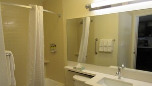 Un baño con bañera, inodoro, lavamanos y espejo.