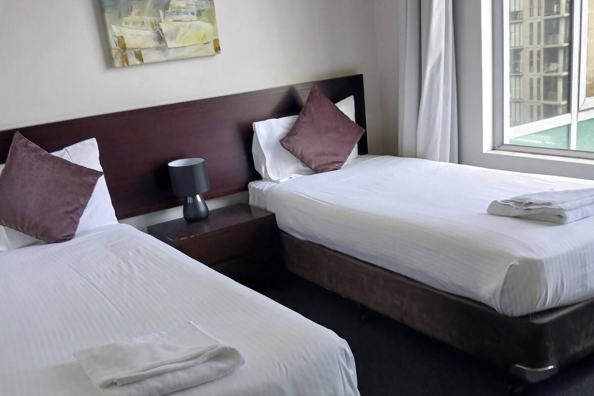 Ein Hotelzimmer mit zwei Betten, einem Nachttisch, einer Lampe und einem Bild an der Wand.