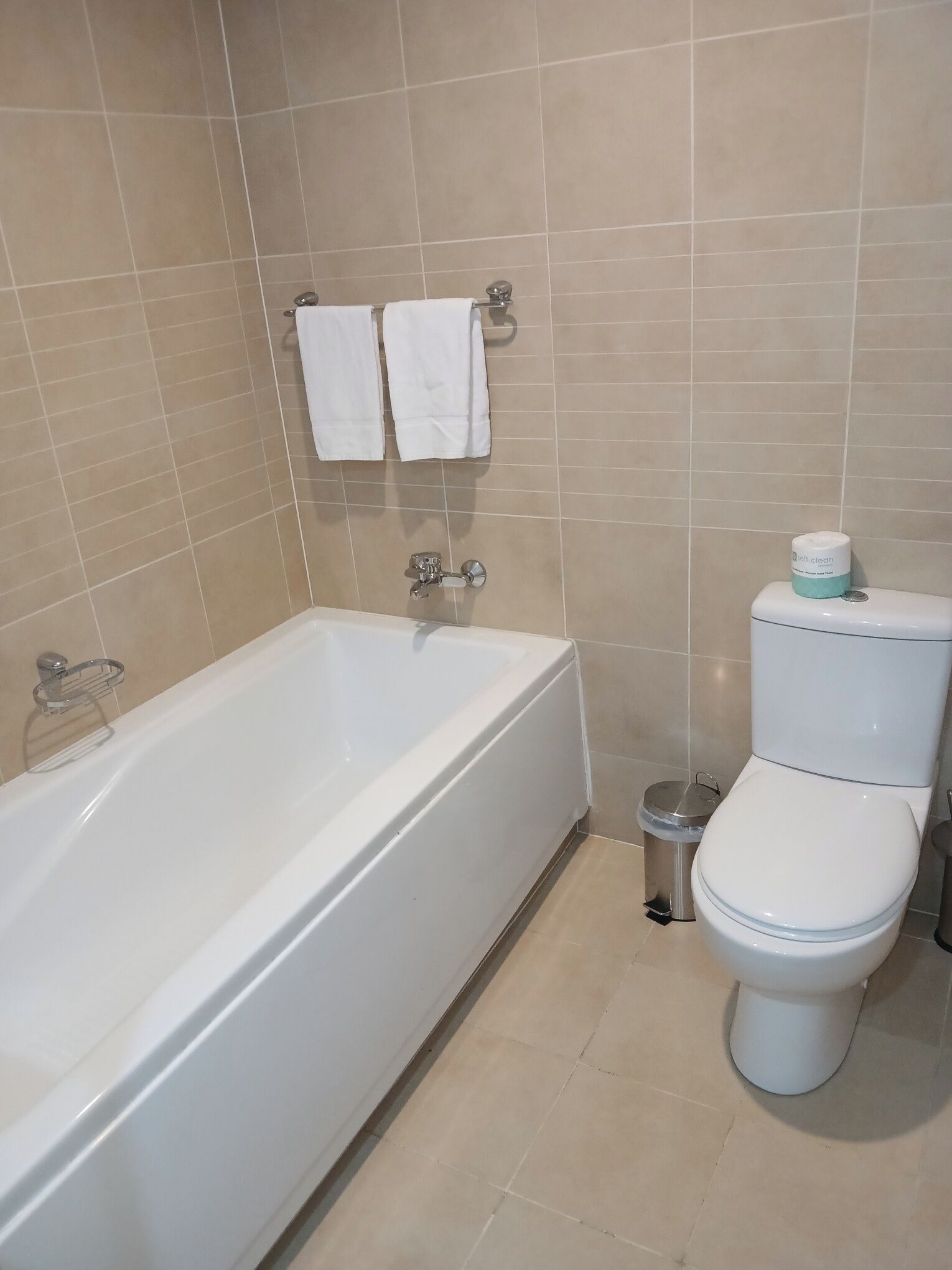 Une salle de bain avec une baignoire, des toilettes et une petite poubelle.