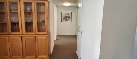 A hallway with a wooden cabinet, a framed artwork on the wall, and a white door.