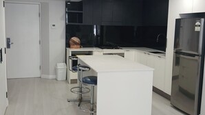 Una cucina moderna con isola centrale, sgabelli da bar, frigorifero in acciaio inossidabile e mobili neri.