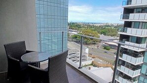 Un balcone con tavolo e sedie, vista sulla città e un grattacielo con facciata in vetro.