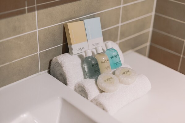 A bathroom with a white bathtub, a set of toiletries including a shower cap, a bottle of shampoo, and a bar of soap.