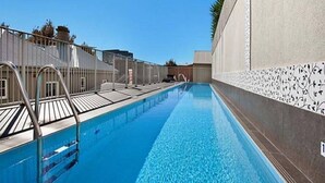 Una piscina con acqua cristallina e blu, circondata da una recinzione e da un muro con motivo decorativo.