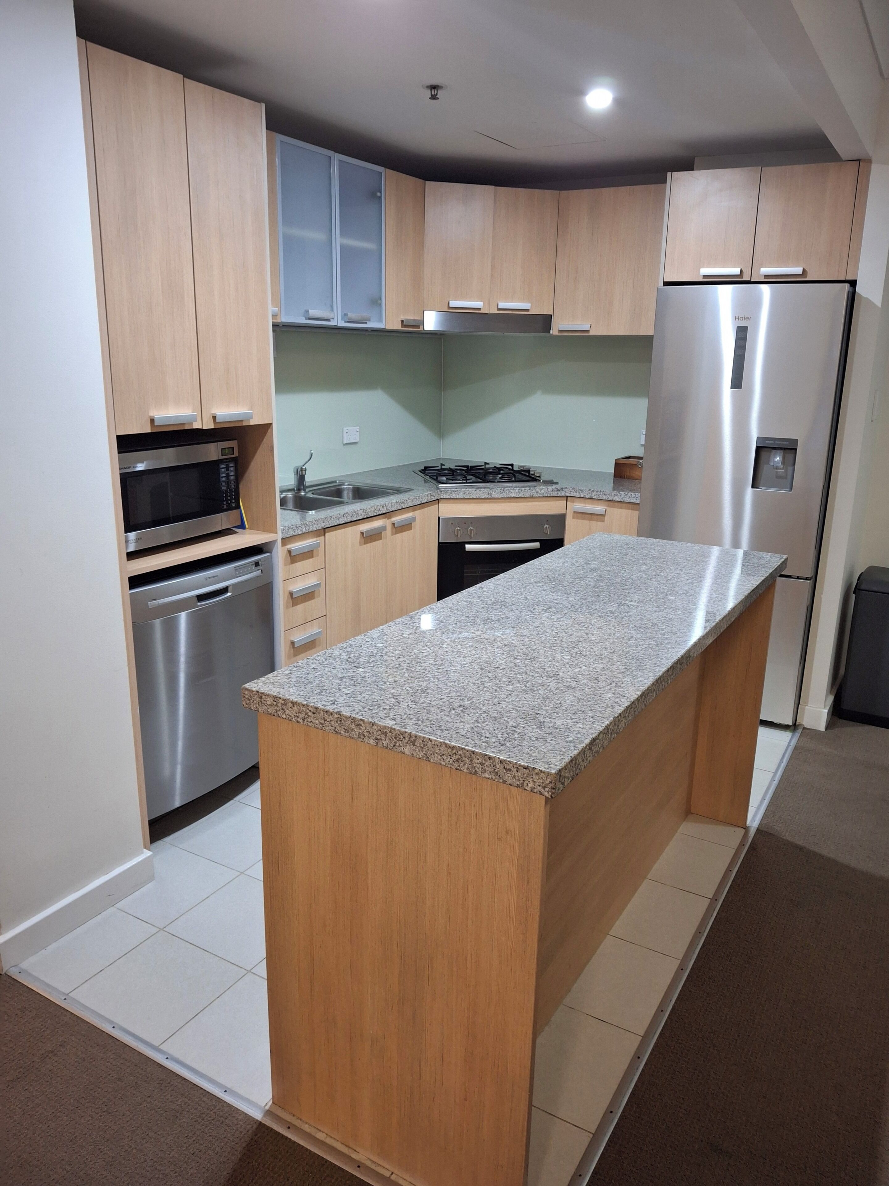 Una cocina moderna con armarios de madera, electrodomésticos de acero inoxidable y una isla con encimera de granito.