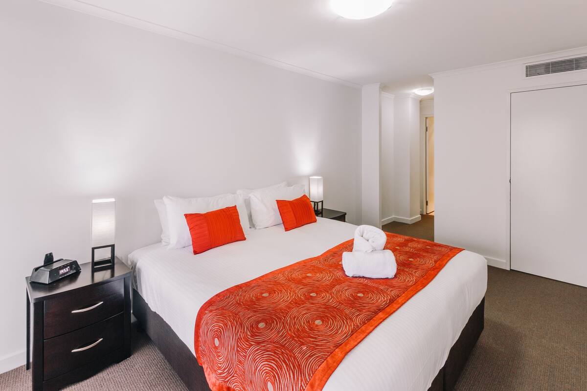 Ein Hotelzimmer mit Bett, Nachttisch, Lampe und Tür.