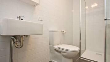 A bathroom with a white sink, toilet, and glass shower enclosure.