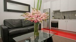 A modern kitchen with white cabinets, a stainless steel refrigerator, and a red countertop. - The Star Apartments (Newcastle West)