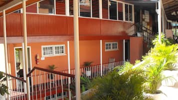 Un edificio de dos plantas con fachada roja, varias ventanas y un balcón con barandilla.