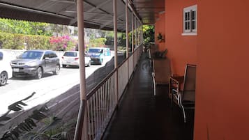 Un espacio al aire libre cubierto con barandilla, plantas en macetas y vista de coches estacionados en la calle.