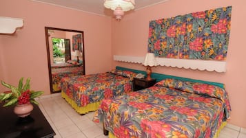 Quarto com duas camas, uma mesinha com um vaso, um espelho e uma pintura floral na parede.