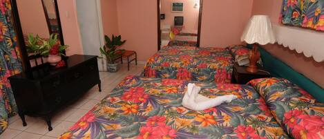 A bedroom with floral bedding, a dresser, a chair, and a bed with a white towel.