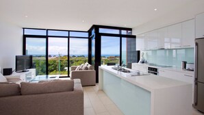 Una cocina moderna con ventanas amplias, un comedor con sofá y vista al mar.