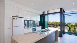 Una cocina moderna con una isla grande, electrodomésticos de acero inoxidable y vistas al exterior.